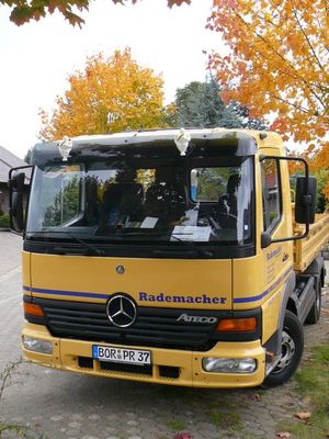 Gelber Mercedes-Lkw Atego mit der Aufschrift Rademacher vor Bäumen mit Herbstlaub