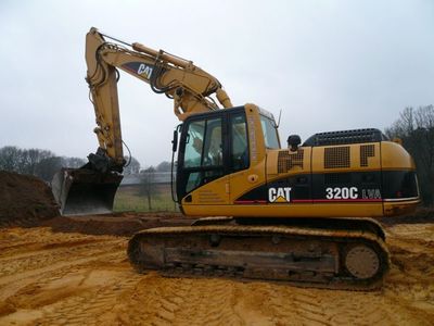 CAT-Kettenbagger 320C mit Tieflöffel auf aufgeschüttetem Sand unter bewölktem Himmel