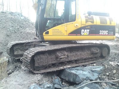 CAT-Kettenbagger 320C steht auf Betonbrocken auf einer Abbruchfläche