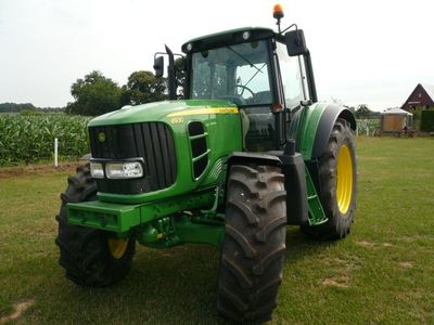 Grüner John-Deere-Traktor mit Rundumleuchte auf einer Wiese